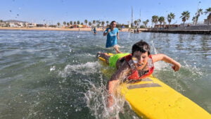 Niño surfeando con su monitora